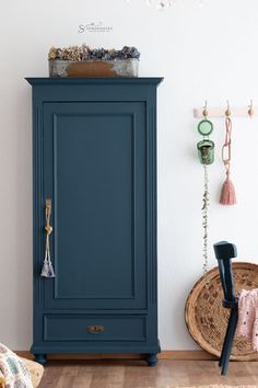 a blue armoire next to a white wall