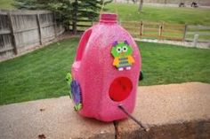 a pink plastic water bottle sitting on top of a cement wall next to a yard