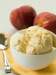 a bowl filled with ice cream next to two apples on a yellow napkin and spoon