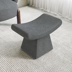 a gray chair and ottoman in a room with white carpeted flooring, windows and curtains