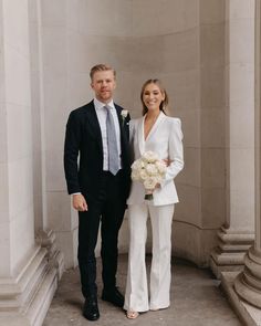 a man and woman standing next to each other in front of some white marble pillars