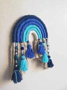 a blue and white wall hanging with some tassels on it's side