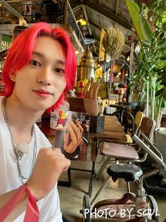 a young man with red hair is holding up a small glass in front of him