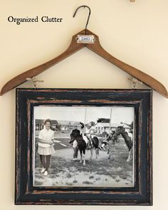 an old black and white photo hangs on a coat hanger with a wooden frame