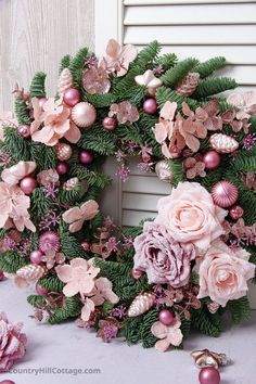 a wreath with pink flowers and green leaves on the front door, surrounded by christmas decorations