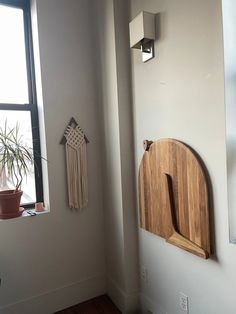 a wooden cutting board mounted to the side of a wall next to a potted plant