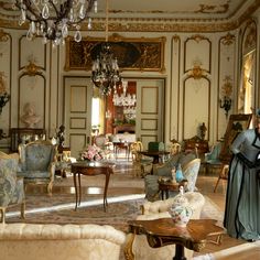 an ornately decorated living room with chandelier and couches in the center