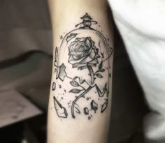 a black and white rose in a glass ball tattoo on the right arm, with arrows around it