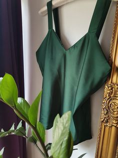 Introducing the Emerald Camisole Top, crafted from a high-quality satin material, this top feels incredibly soft and silky against the skin, making it the perfect choice for special occasions or a night out on the town. The vibrant emerald green color is sure to turn heads and add a pop of color to any outfit. The V-neckline is both flattering and feminine, and the simple, minimalist design makes this top versatile and easy to style with a variety of bottoms. Whether you dress it up with a pair Sleeveless Evening Tops With Built-in Bra, Elegant Green V-neck Camisole, Fitted Sleeveless Satin Tank Top, Fitted Satin Finish Sleeveless Tank Top, Silk Cami Tank Top With Built-in Bra, Solid Color Satin Camisole For Night Out, Satin Padded Blouse For Night Out, Night Out Satin Finish Camisole, Padded Satin Blouse For Night Out