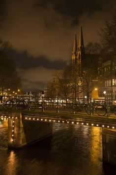 a bridge over a river in front of a church at night