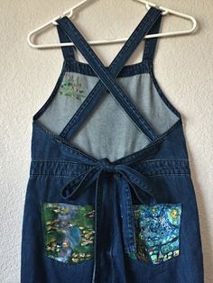 a pair of jean overalls hanging up on a wall with the back pocket open