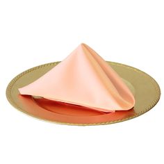 an orange napkin sits on top of a gold plate with a pink napkin folded over it