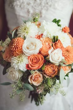 an orange and white bridal bouquet with greenery