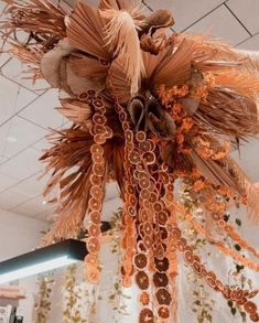 a chandelier hanging from the ceiling is made out of orange and brown feathers