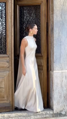 a woman in a white dress is standing at the entrance to a building with an open door