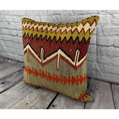 a decorative pillow on a wooden floor next to a white brick wall and wood planks