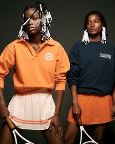 two women standing next to each other with tennis rackets in their hands and wearing ear rings