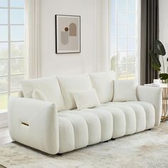 a white couch sitting in front of a window next to a rug on top of a floor