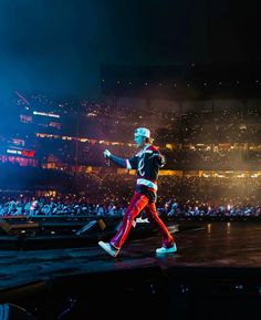 a man walking across a stage in front of a crowd at a sporting event with bright colored pants