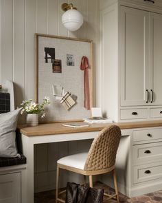 a white desk with a chair and some pictures on the wall above it in a home office