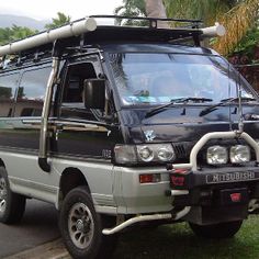 a black van parked on the side of a road next to a lush green field