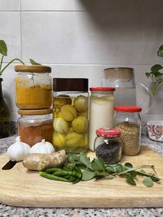 several jars filled with food sitting on top of a wooden cutting board next to green beans