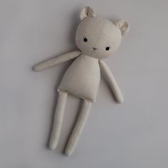 a white teddy bear laying on top of a gray surface with its eyes open and ears closed