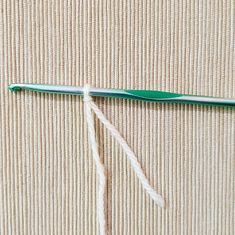 a green crochet hook with white yarn on it