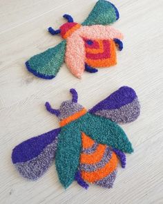 two small knitted bugs sitting on top of a wooden floor