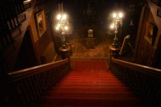 the stairs are lit up at night with two lights on each side and red carpet