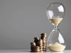 an hourglass sitting next to stacks of coins