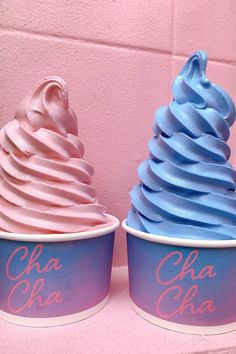 two ice cream cones with blue and pink frosting on top, one has the word cha cha written in cursive writing