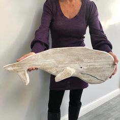 a woman holding a carved wooden fish