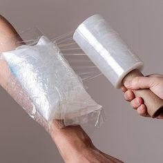 two hands holding plastic bags and one hand is wrapped in plastic wrap with a rubber band