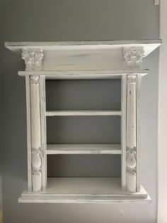 an old white painted bookcase with decorative carvings on the top and bottom shelf,