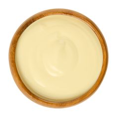 a wooden bowl filled with cream on top of a white surface