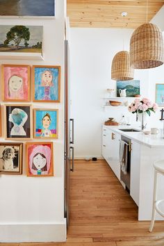 a kitchen with pictures on the wall and an open door leading to another room that has white cabinets