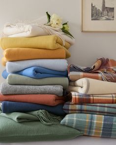 a stack of folded towels sitting on top of a table next to a vase with flowers