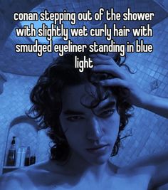 a man with curly hair standing in the shower and holding his hand on his head