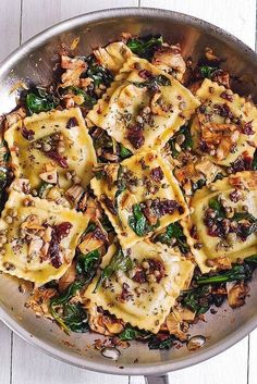 a pan filled with ravioli and spinach covered in cheese