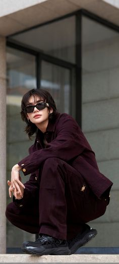 a man with sunglasses on his face sitting on a ledge in front of a building