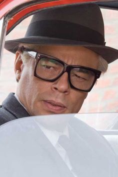 a man wearing glasses and a hat sitting in a car