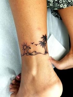 a woman's foot with a small palm tree and wave tattoo on the ankle