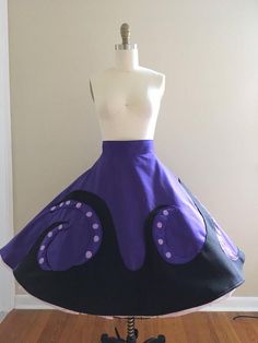 a purple and black skirt on a mannequin head stand in front of a white wall