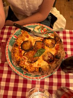 a pizza sitting on top of a red and white checkered tablecloth covered table