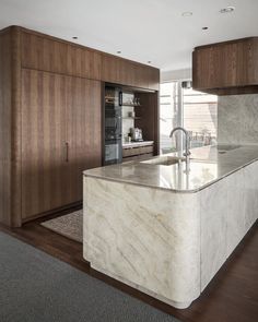 a large kitchen with marble counter tops and wooden cabinetry, along with hardwood floors