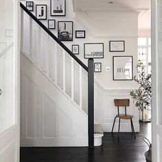 a staircase with pictures on the wall and a chair next to it in front of an open door