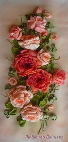 an arrangement of pink and red roses on a white surface with green leaves in the middle