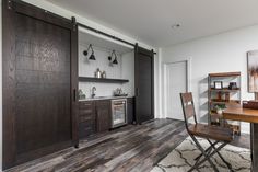 an open sliding door in a kitchen with wooden floors and walls, along with a dining room table