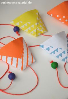 three paper kites are on the table with string attached to them and some beads